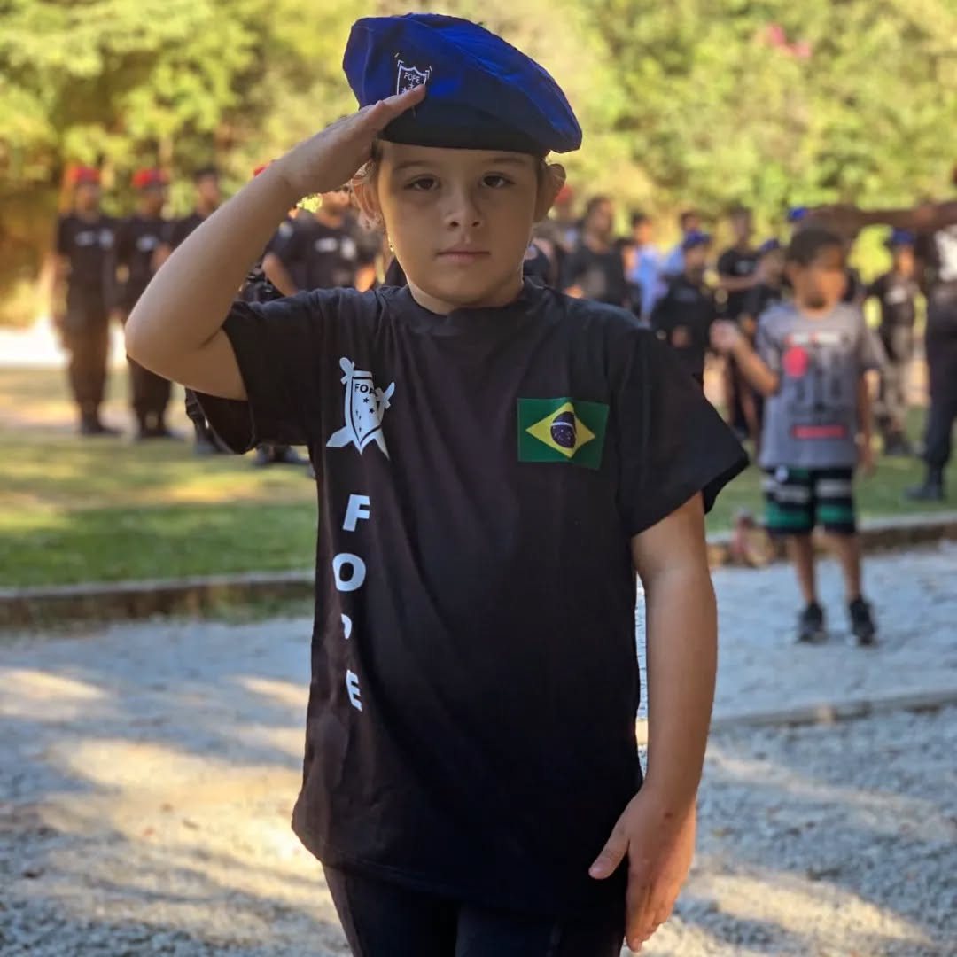 Aluna da FOPE prestando continência, de boina e uniforme, diante da formatura