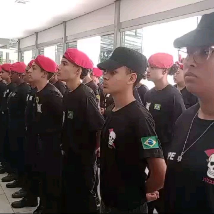 Alunos em forma com boinas vermelhas durante cerimônia